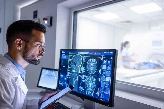 Modern neuroscience research laboratory featuring fMRI brain imaging equipment, computer monitors displaying brain scans, and researchers analyzing hypnotherapy study results